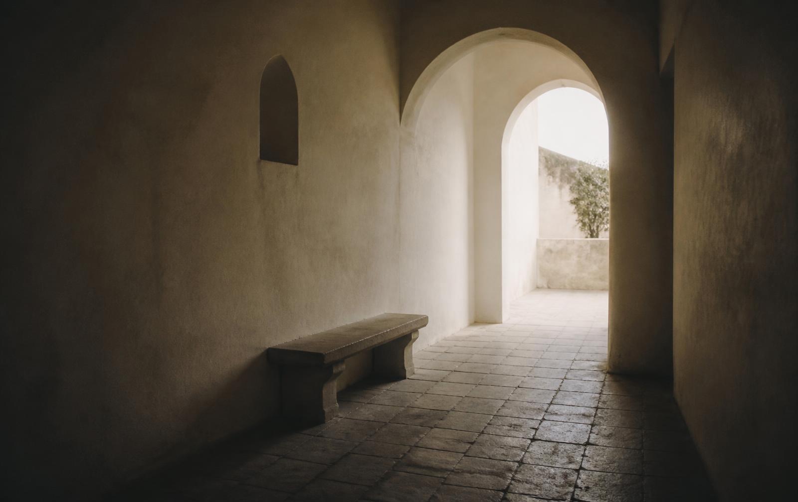 Corridoio in intonaco chiaro con arco aperto sulla luce